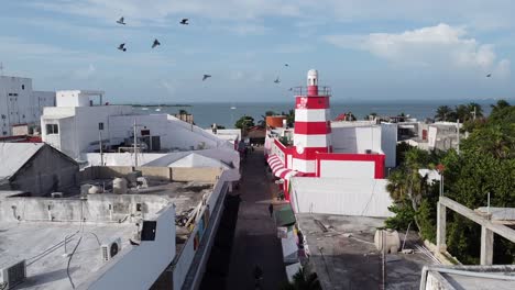 A-drone-shot-of-a-beautiful-white-and-red-colored-lighthouse-at-the-shore-of-an-ocean