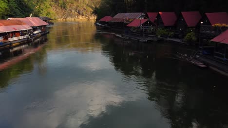 Eine-Atemberaubende-Drohnenaufnahme,-Die-Schnell-An-Einem-Charmanten-Schwimmenden-Dorf-Vorbei-Und-über-Einen-Fluss-Im-Dschungel-Des-Sai-Yok-Nationalparks-In-Der-Provinz-Kanchanaburi-In-Thailand-Fliegt