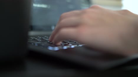 Caucasian-guy-typing-on-laptop-computer,-shallow-focus-low-side-angle