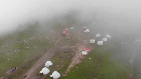 Fog-covered-Baboon-Valley-in-Kashmir,-Pakistan,-is-seen-from-above,-and-several-tents-have-been-set-up-for-the-hikers-to-rest