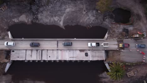 Line-of-cars-crossing-dangerous-bridge-under-construction-in-Uruguay,-South-America