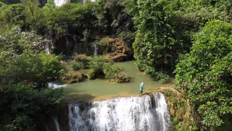 A-man-is-walking-on-the-edge-of-Thi-Lo-Su-Waterfall,-located-deep-in-the-jungle,-off-the-beaten-track-of-North-Thailand-in-the-area-of-Umphang-in-Southeast-Asia