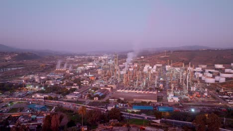 Aerial-dolly-in-of-Concon-open-field-area-at-golden-hour-and-smoke-from-ENAP-Aconcagua-refinery,-Valparaiso,-Chile