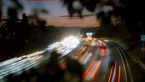 A-Time-Lapse-of-Freeway-Traffic-at-Sunset-with-Foliage-in-the-Foreground