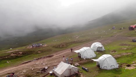 Ein-Von-Einer-Drohne-Aufgenommenes-Luftvideo-Zeigt-Das-In-Nebel-Gehüllte-Baboon-Top-Neelum-Valley-In-Pakistan,-In-Dem-Fünf-Zelte-Mit-Zahlreichen-Bewohnern-Aufgestellt-Sind