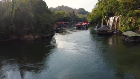 Eine-Wunderbare-4k-drohnenaufnahme-Eines-Flusses-Im-Dschungel-Thailands,-Mit-Blick-Auf-Ein-Kleines-Schwimmendes-Dorf-Und-Einen-Wunderschönen-Tropischen-Wasserfall-Im-Sai-Yok-Nationalpark-In-Asien