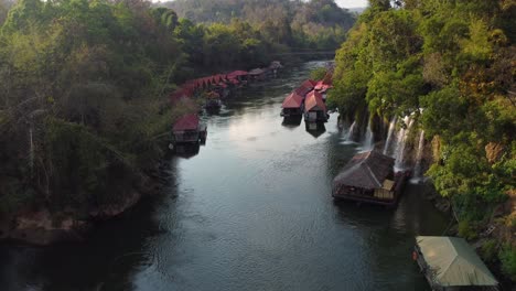A-stunning-view-of-a-river-in-Thailand-in-the-middle-of-the-jungle,-with-waterfalls-and-a-charming-floating-village-on-the-side-of-the-river---In-Sai-Yok-National-Park-in-the-province-of-Kanchanaburi