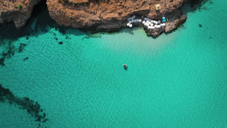 A-small-boat-paddling-in-the-clear-blue-water-in-Blue-Lagoon-on-Comino-Island-in-Malta