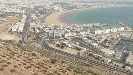 Cable-car-of-the-aerial-tramway-connecting-Oufella-peak-and-Agadir-city-in-Morocco,-overlooking-a-panoramic-view-of-the-beach-2