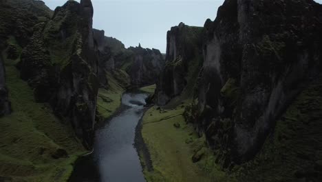 Drone-shot-flying-low-through-Fjaðrárgljúfur-rock-canyon-with-river-below-in-Iceland-in-4k