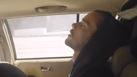 Attractive-young-tired-white-man-gen-Z-millennial-falls-asleep-in-the-back-of-car-with-mouth-open-during-a-road-trip-van-life-adventure-in-slow-motion-1