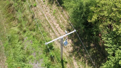 Extreme-close-up-bird's-eye-aerial-panning-shot-of-a-rural-utility-pole-and-powerline-inspection