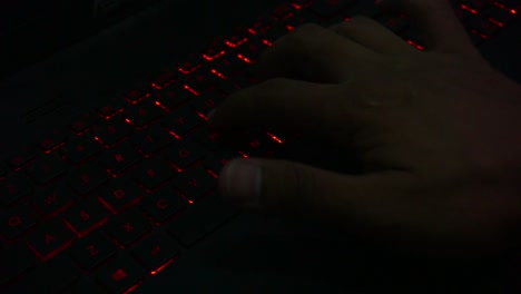 Draufsicht-Der-Hand,-Die-Auf-Der-Tastatur-Mit-Roter-Beleuchtung-Des-Laptops-In-Einem-Dunklen-Raum-Tippt,-Nahaufnahme-1