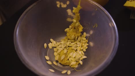Woman-Putting-Scraped-Pulp-And-Seeds-Of-A-Yellow-Pumpkin-Into-A-Bowl--Halloween-Season