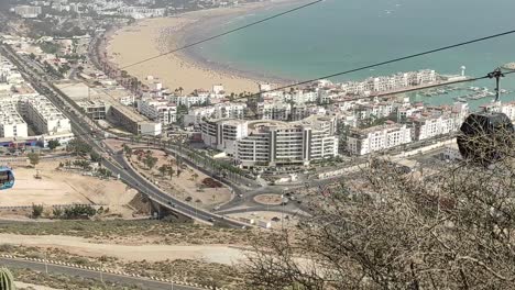 Cable-car-of-the-aerial-tramway-connecting-Oufella-peak-and-Agadir-city-in-Morocco,-overlooking-a-panoramic-view-of-the-beach-12