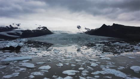 Drone-Volando-Hacia-Un-Gran-Glaciar-Sobre-Un-Lago-Con-Trozos-De-Hielo-En-Islandia-4k
