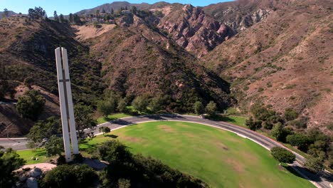 The-Phillips-theme-tower-at-Pepperdine-university-surrounded-by-red-mountain-slopes-aerial-reversing-shot