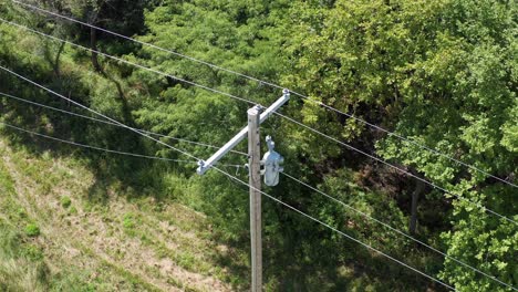 Extreme-close-up-aerial-shot-tilting-down-on-a-rural-utility-pole-and-powerline-inspection