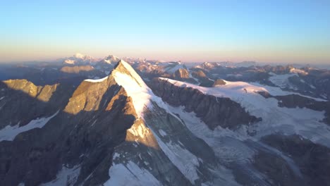 Wide,-high-altitude-aerial-view-of-The-Matterhorn-at-sunrise-with-golden-light-on-snow-covered-peak