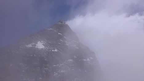 Aerial-view-of-The-Matterhorn-as-drone-emerges-from-clouds-looking-up-at-the-peak-of-Mont-Cervin,-Mount-Cervino