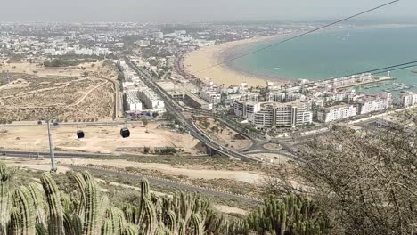 Cable-car-of-the-aerial-tramway-connecting-Oufella-peak-and-Agadir-city-in-Morocco,-overlooking-a-panoramic-view-of-the-beach-11