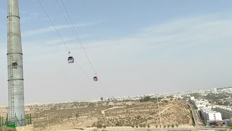 Cable-car-of-the-aerial-tramway-connecting-Oufella-peak-and-Agadir-city-in-Morocco,-overlooking-a-panoramic-view-of-the-beach-5