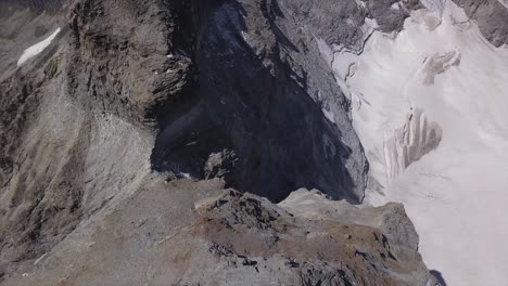 Aerial-view-from-drone-looking-down-and-rotating-high-over-mountains-with-snow-and-ice-covered-slope