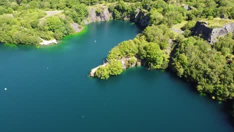 Aerial-view-Dorothea-slate-mining-quarry-forest-in-Snowdonia-valley-with-gorgeous-sunny-blue-lake