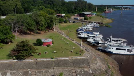 Aerial-view-of-a-group-of-white-yachts-docked-at-an-isolated-dock,-next-to-trees,-forest,-nature,-a-camping-and-a-couple-of-parking-slots