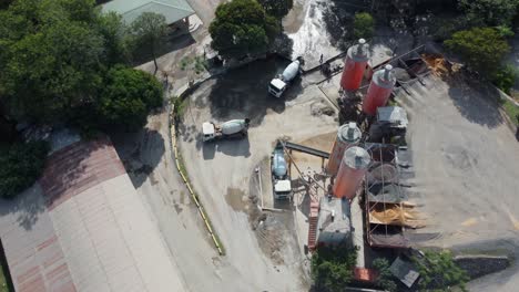 Concrete-mixer-trucks-moving-and-working-on-industrial-zone-or-construction-site,-aerial-view-with-forward-motion