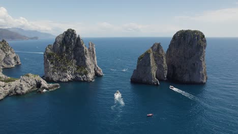 Vista-Aérea-De-Barcos-Navegando-En-El-Mar-Con-Formación-Rocosa-De-Farallones-En-Capri,-Italia