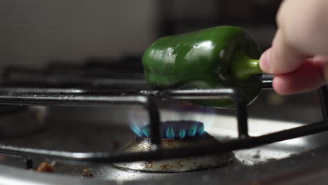 Hand-Puts-Whole-Green-Bell-Pepper-On-The-Stove-With-Low-Fire-For-Roasting