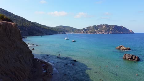 Ibiza-secret-top-ten-beaches-number-One:
Breathtaking-aerial-view-flight-pedestal-down-drone-footage
of-Aigües-Blanques-cliff-hippie-beach-summer-day-july-2022