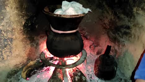 Moroccan-couscous-cooking-on-a-couscoussier-steamer-to-steam-it
on-a-wooden-fire-in-a-fireplace,-smoke-and-flame-surround-the-pot