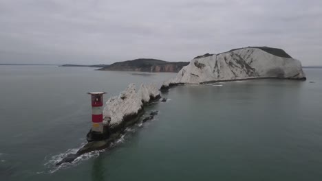 Aerial-drone-flight-heading-over-the-red-and-white-lighthouse-towards-the-white-cliffs-of-The-Needles-in-The-Isle-of-Wight