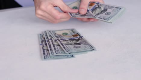 Bank-Teller-Counting-New-One-Hundred-Dollar-Bills-On-White-Table