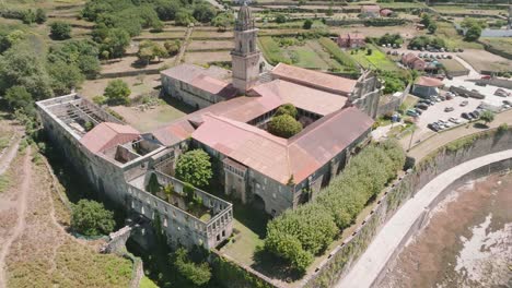 Luftaufnahme-Eines-Beschädigten-Historischen-Klosters-In-Santa-Maria-De-Oia-Mit-Blick-Auf-Wenige-Autos,-Die-Im-Hintergrund-Geparkt-Sind