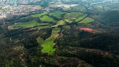 Luftaufnahme-Der-Grünen-Wiese-Am-Fuße-Des-Berges-In-Der-Nähe-Der-Wohnhäuser-In-Puchuncavi,-Chile