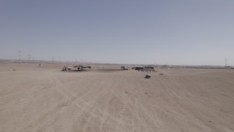 Bedouin-residential-tents-without-a-permit-in-a-remote-and-desert-area,-near-a-highway-and-large-power-poles,-dry-land-without-crops,-push-in-shot