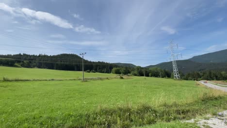 Power-lines-through-nature-hills-mountains-during-bright-summer-day