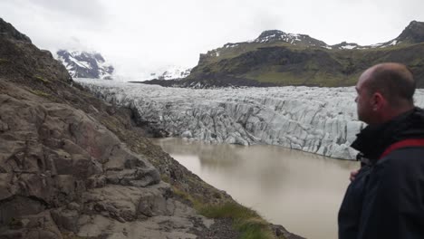 Iceland-glacier-with-man-standing,-turning-and-walking-in-slow-motion