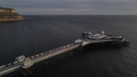 Aerial-drone-flight-heading-out-ove-the-pier-in-Llandudno-wales-showing-The-Great-Orme-and-coastline-in-the-background