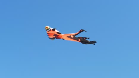 Low-angle-shot-of-orange-octopus-kite-flying-high-summer-clear-blue-sky-in-Vietnam-at-daytime