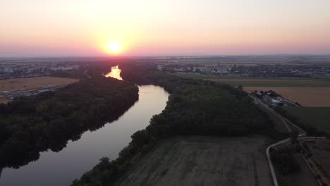 Fluss-Schlängelt-Sich-Durch-Agrarlandschaft-In-Richtung-Lebendigen-Sonnenuntergangs