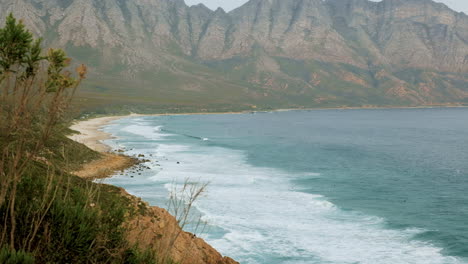 Kogel-Bay-beach-and-popular-Caves-surf-spot,-surrounded-by-mountains