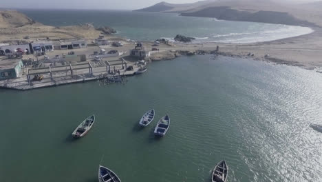 Langer-Drohnenschuss-Vom-Himmel-Einiger-Boote,-Die-Am-Ufer-Einer-Peruanischen-Insel-Schwimmen
