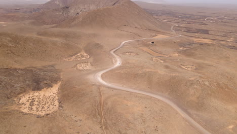 Ein-Einsames-Fahrzeug,-Das-Auf-Einer-Langen-Und-Kurvenreichen-Wüstenstraße-In-Fuerteventura,-Kanarische-Inseln,-Spanien,-Unterwegs-Ist