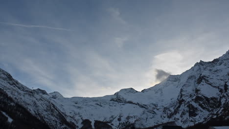Timelapse:-large-view-of-a-mountain-range-in-the-swiss-alps,-Saas-Fee,-Rocky-snowy-summits-in-the-evening,-moving-clouds
