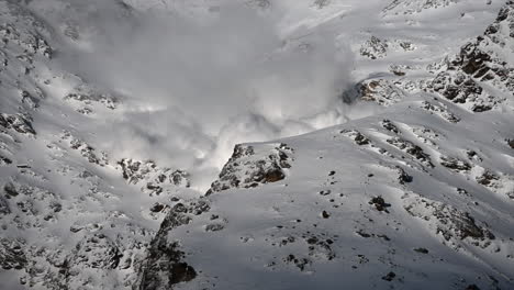 A-large-avalanche-Made-with-power-goes-down-a-rocky-Swiss-alps-Mountain-next-to-ski-slopes,-science