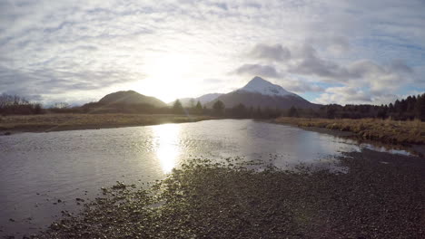 Ein-Zeitraffer-Der-Untergehenden-Sonne-Und-Sich-Bewegender-Wolken-über-Den-Bergen-Und-Einem-Lachsfluss-Auf-Kodiak-Island-Alaska